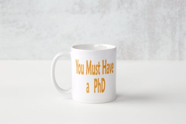 A white mug with the words " you must have a phd ".