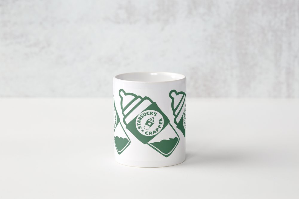 A white cup with green designs on it.