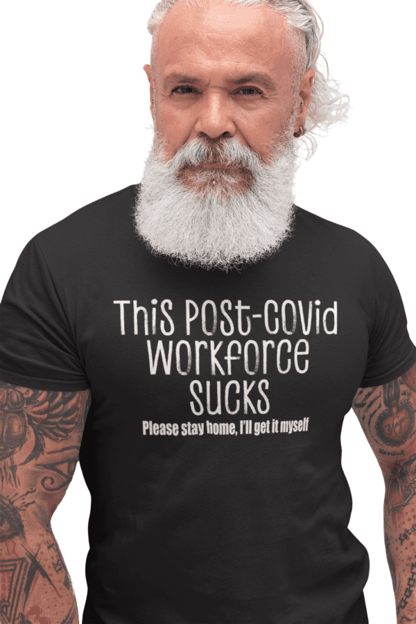 A man with a beard and tattoos wearing a shirt that says " this post-covid workforce sucks ".